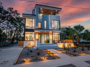 Een modern huis met twee verdiepingen, een balkon, grote ramen en een helder verlichte entree.