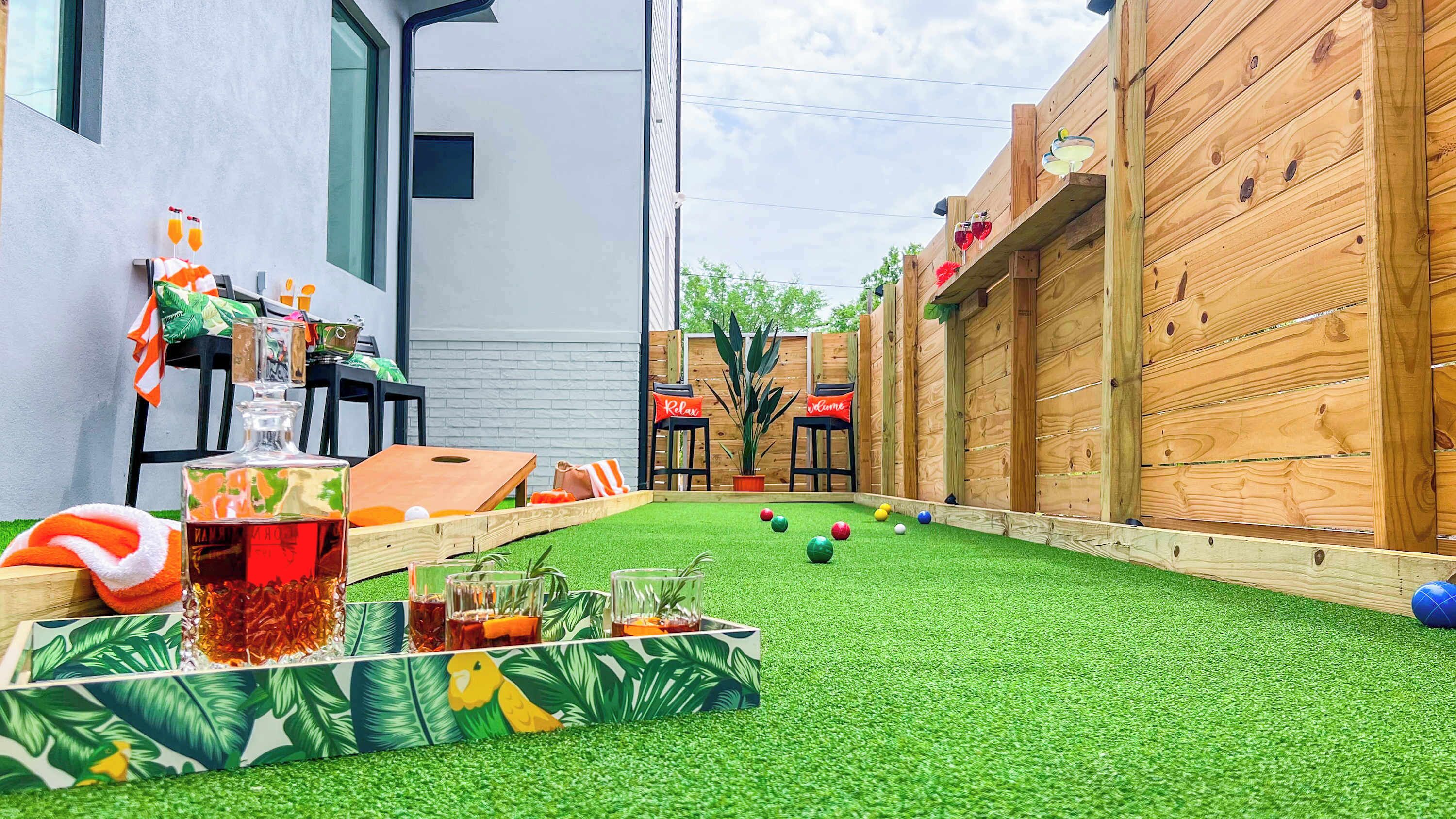 Un jardin avec une pelouse artificielle, une table de ping-pong et un petit espace aménagé avec des plantes en pot.