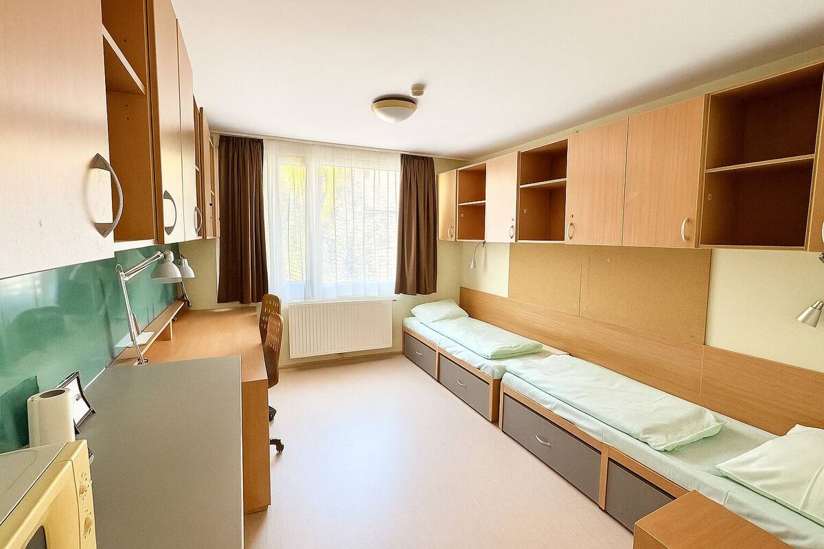 Quarto compacto com cozinha compacta, uma cama e janela com cortinas.