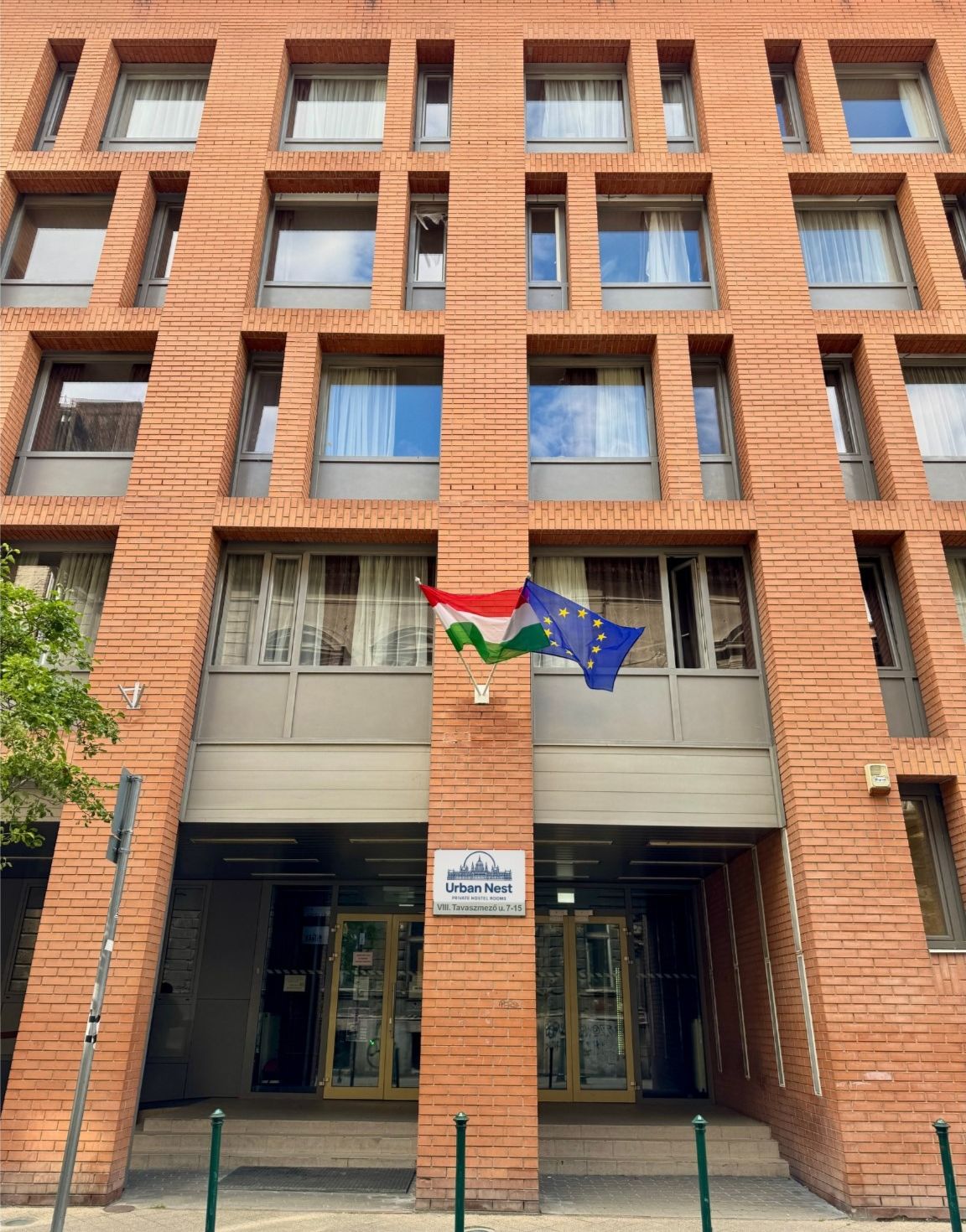 Un edificio de ladrillo con un letrero que dice “Urban Nest” y una bandera sobre la entrada.
