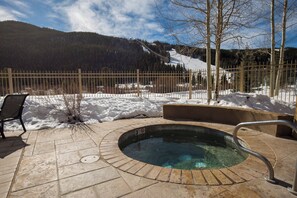 Relax by the serene pool surrounded by a deck and a forested mountain view.