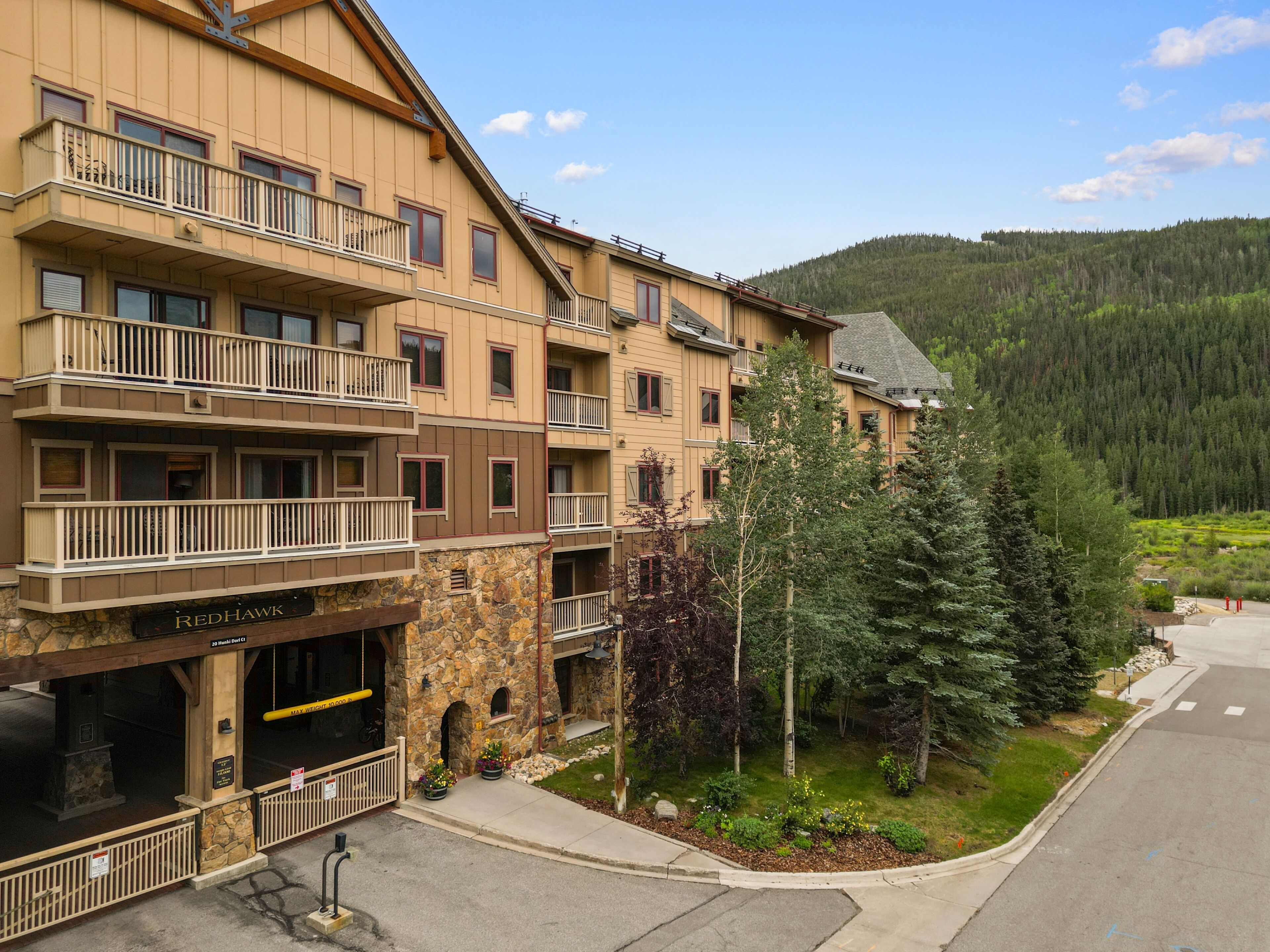Un hôtel à plusieurs étages, doté de balcons, d’une façade en pierre et offrant une vue sur une montagne boisée.