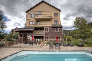 A two-story building with a pool and outdoor seating area.