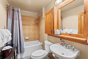 A bathroom with a bathtub, toilet, sink, and wooden cabinets.