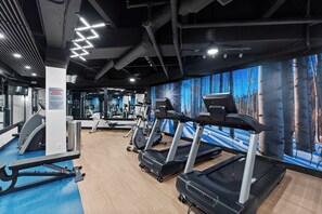 Ein Fitnessstudio mit Laufbändern, Trainingsgeräten und einem großen Spiegel.
