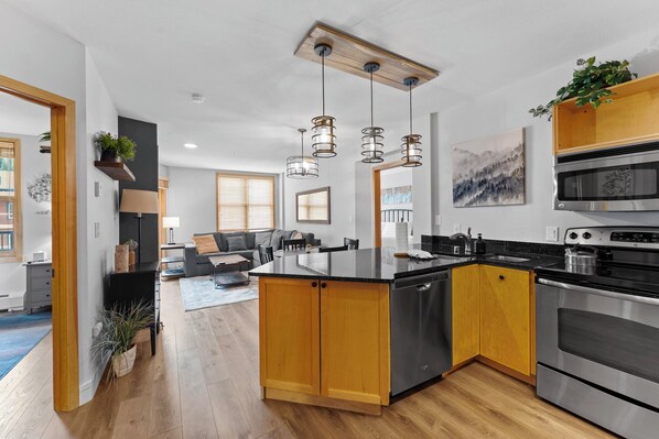 A modern kitchen with wooden cabinets, stainless steel appliances, and pendant lighting. - Prime River Run Location: 2-Min Walk to the Gondola! (Keystone)