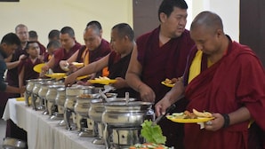 Des moines servent de la nourriture à un buffet proposant de nombreux plats et récipients.