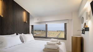 Een moderne hotelkamer met een groot bed, uitzicht op het landschap en een minimalistische inrichting.