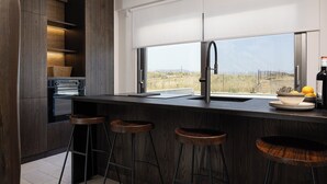 Een moderne keuken met een groot raam, donkere houten keukenkastjes en barstoelen.