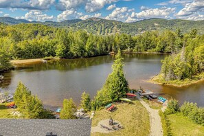 A lakeside property with a dock, kayaks, a deck chair, and a cabin.