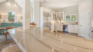 A spacious kitchen with a marble countertop, white cabinetry, and a modern stainless steel refrigerator. - Oceanfront, private boardwalk and pool (Kiawah Island)