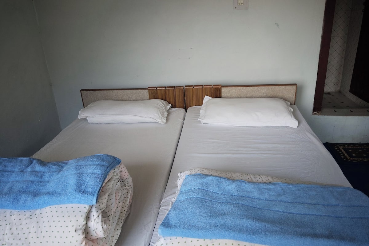 A twin room with two beds, each with a blue towel and white bedding.