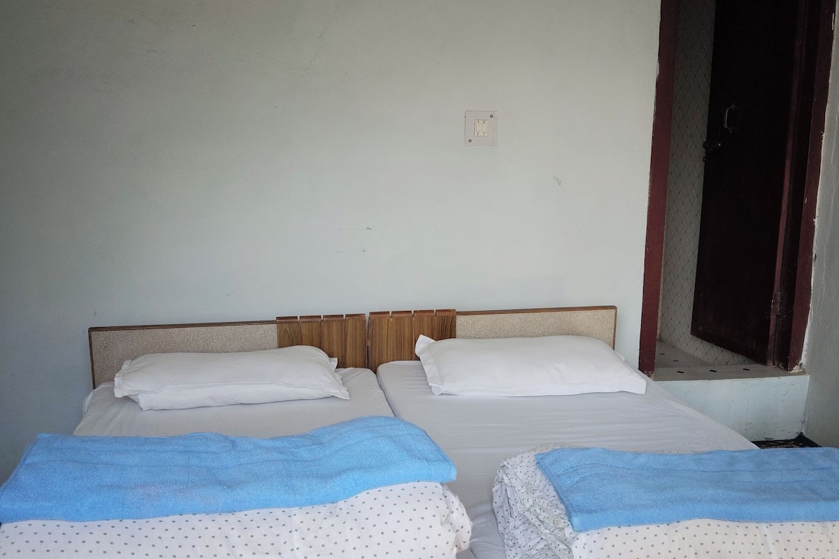 A room with two beds, each with a blue blanket and white polka dot sheets.