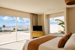 Habitación de hotel con una cama grande, un televisor sobre un mueble de madera y un balcón con vistas a la ciudad.