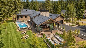 Une maison moderne dotée d’une piscine, d’un espace salon extérieur et d’un patio couvert.