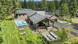 Une maison moderne dotée d’une grande terrasse, d’une piscine et d’une cheminée en pierre.