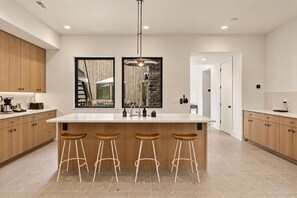 Une cuisine moderne dotée d’un grand îlot central, de tabourets de bar et d’un luminaire suspendu.