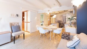 Een moderne woonkamer met een eethoek, een bank, een fauteuil en een kleine tafel.