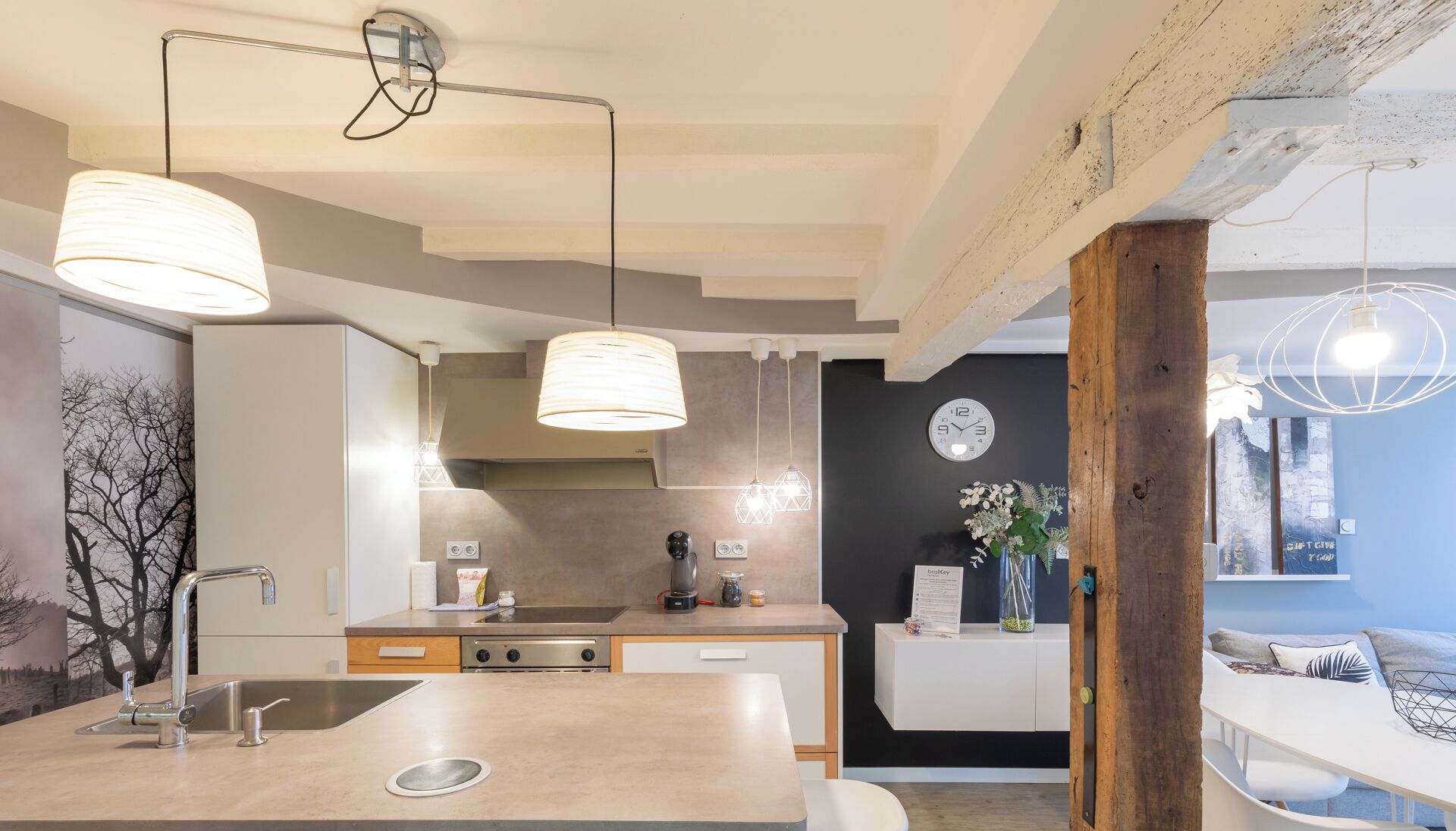 A modern kitchen with a central island, pendant lighting, and a visible clock on the wall.