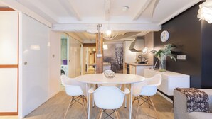 Een moderne keuken met een ronde eettafel, witte stoelen en een klok aan de muur.
