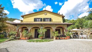 A two-story house with a yellow facade, stone arches, and a tiled roof. - Amazing home in Cortona (Cortona)