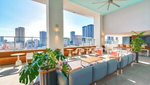 A rooftop lounge with seating, tables, and a city view.