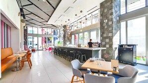 A modern restaurant with a bar area, seating arrangements, and a view of the street.