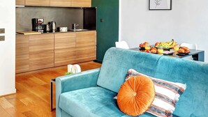 Un espace de vie moderne avec un canapé bleu, une cuisine en bois et un coin repas où sont servis des articles pour le petit-déjeuner.
