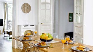 Un comedor con una mesa de madera, sillas transparentes y una lámpara colgante.