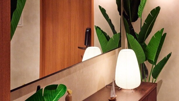 A modern bathroom with a wooden vanity, a large mirror, and a potted plant. - Gold Stage TENJIN (Fukuoka)