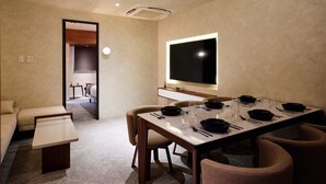 A modern hotel room with a dining area, a TV mounted on the wall, and a cozy seating arrangement. - Gold Stage TENJIN (Fukuoka)