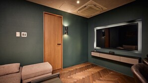 A room with a herringbone-patterned wooden floor, a large mirror above a built-in TV, and a wooden door. - Gold Stage TENJIN (Fukuoka)