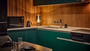 A modern kitchen with a microwave, kettle, and a bright pendant light. - Gold Stage TENJIN (Fukuoka)