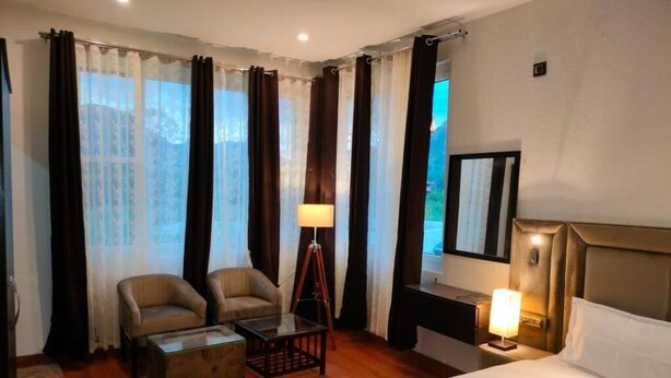 Habitación de hotel con una cama, dos sillones, una mesita, un escritorio y una lámpara.