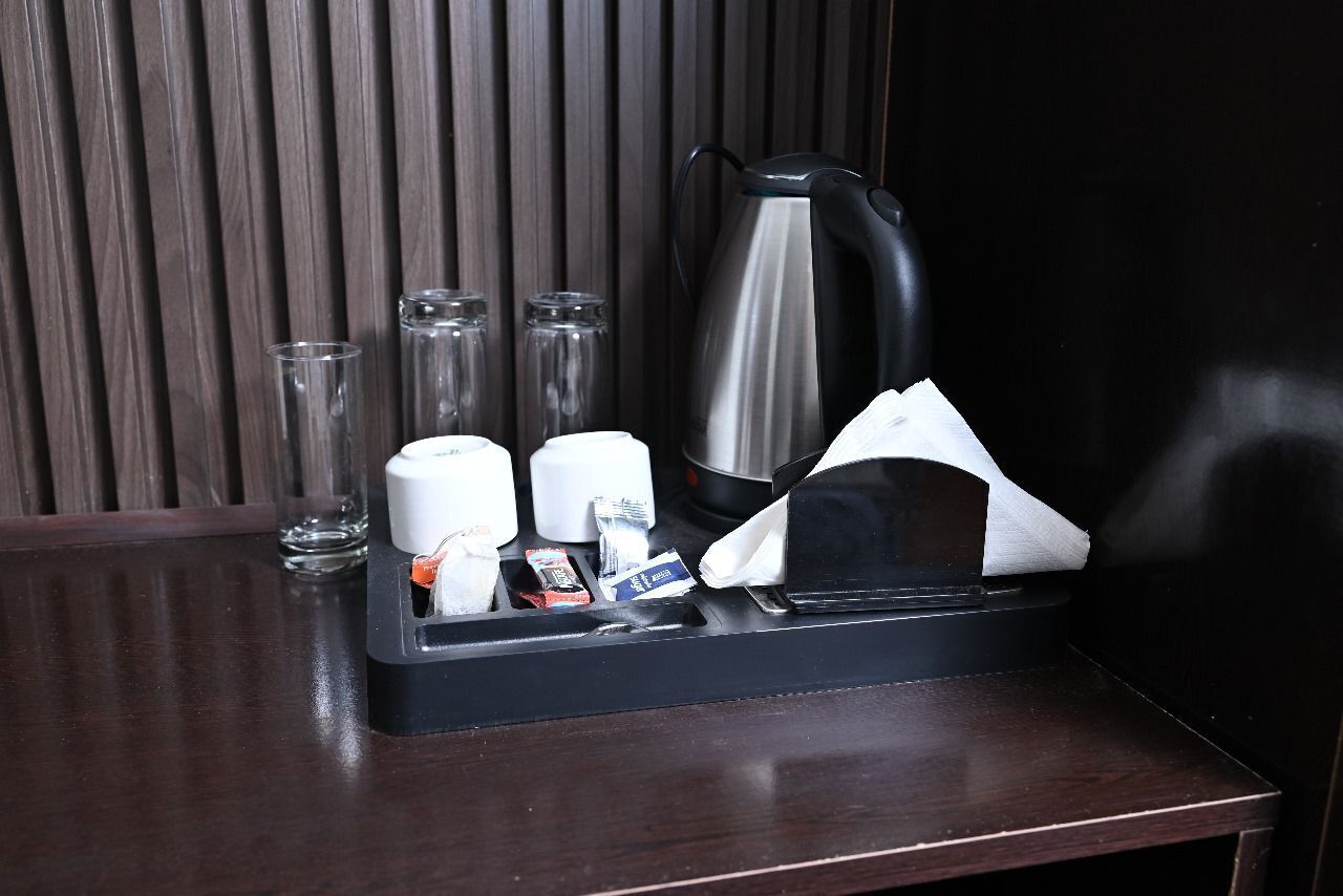 Minibar de un hotel con cafetera, vasos y artículos de aseo.