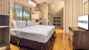 Ein Schlafzimmer mit einem großen Bett, Holzwänden, einem Deckenventilator und einem Fernseher auf einer Holzkommode.