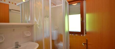 Un baño con lavamanos, espejo, cabina de ducha y ventana.