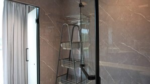 A bathroom with a glass shower enclosure, marble walls, and a metal shelf unit. - Rustic Ranch and the Vessels of tomorrow (Satin)