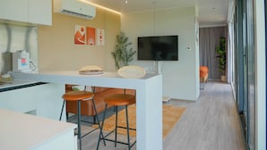 A modern kitchen with a central island, bar stools, a flat-screen TV, and a coffee machine. - Rustic Ranch and the Vessels of tomorrow (Satin)