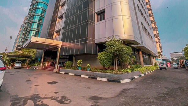 A modern high-rise building with a curved facade and a covered entrance area. - GiiA Sanno Hotel Pluit Jakarta (Jakarta)