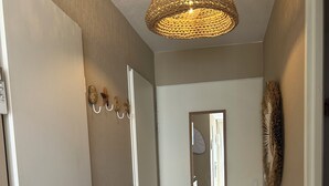 A hallway with a white door, a mirror, and a textured ceiling light fixture. - Richelieu vue mer "Soleil, beach 300 m, swimming pool, wifi (Agde)