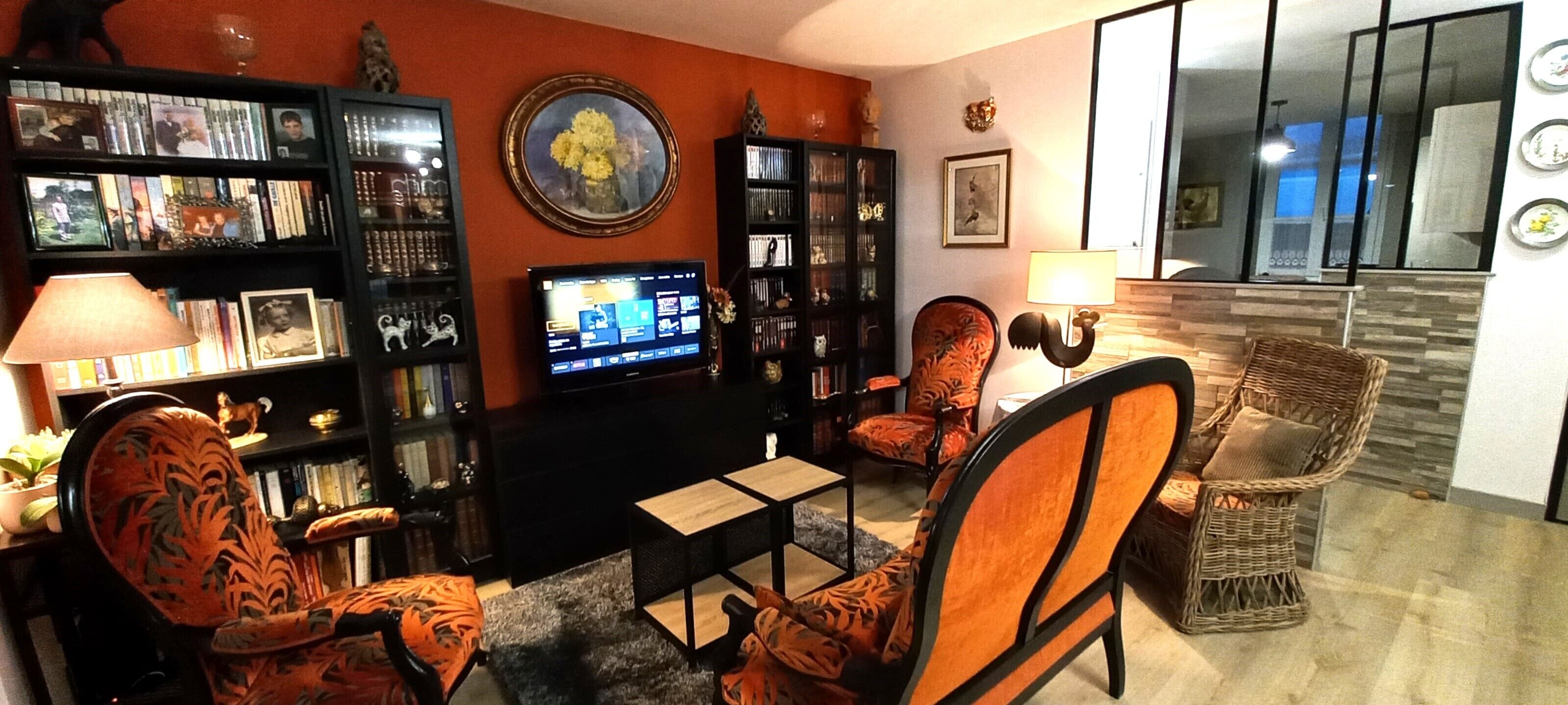 A living room with a television, bookshelves, and two wicker chairs.