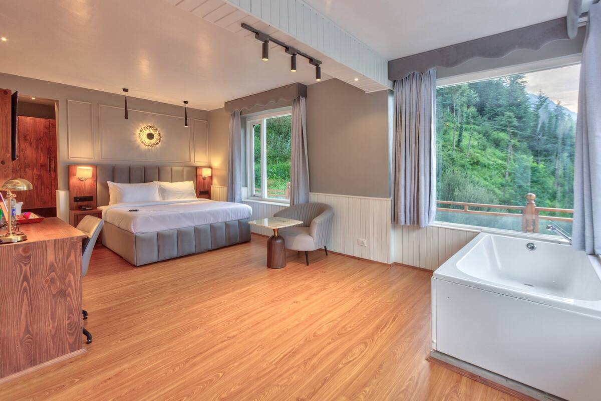 Una habitación de hotel moderna con una cama grande, un área de descanso, un escritorio y una bañera.