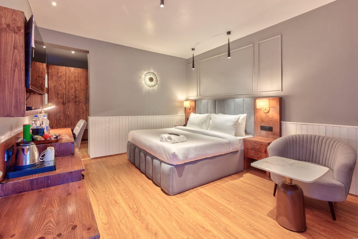 Un dormitorio moderno con una cama grande, mesitas de noche, una silla y un televisor.