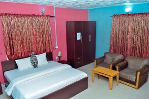 Una habitación de hotel con cama, armario, dos sillones y una mesita.