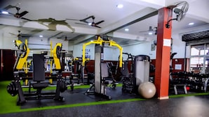 Ein Fitnessraum mit verschiedenen Trainingsgeräten, darunter Kraftgeräte und Kurzhanteln.