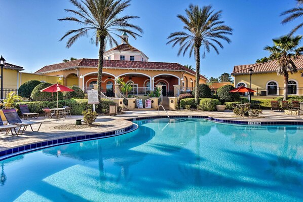 A swimming pool with a curved edge, palm trees, and outdoor seating.