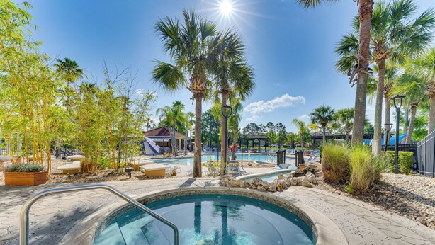 A swimming pool with a hot tub, surrounded by palm trees and lounge chairs. - 7 Mi to Wdw, Resort Perks: Retreat in Kissimmee! (Kissimmee)