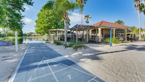 A beachside area with a shuffleboard court, palm trees, and a building with a red-tiled roof. - 7 Mi to Wdw, Resort Perks: Retreat in Kissimmee! (Kissimmee)