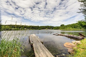 Eine Holzstele, die sich in einen ruhigen Fluss hinein erstreckt, umgeben von üppiger Vegetation und Bäumen.